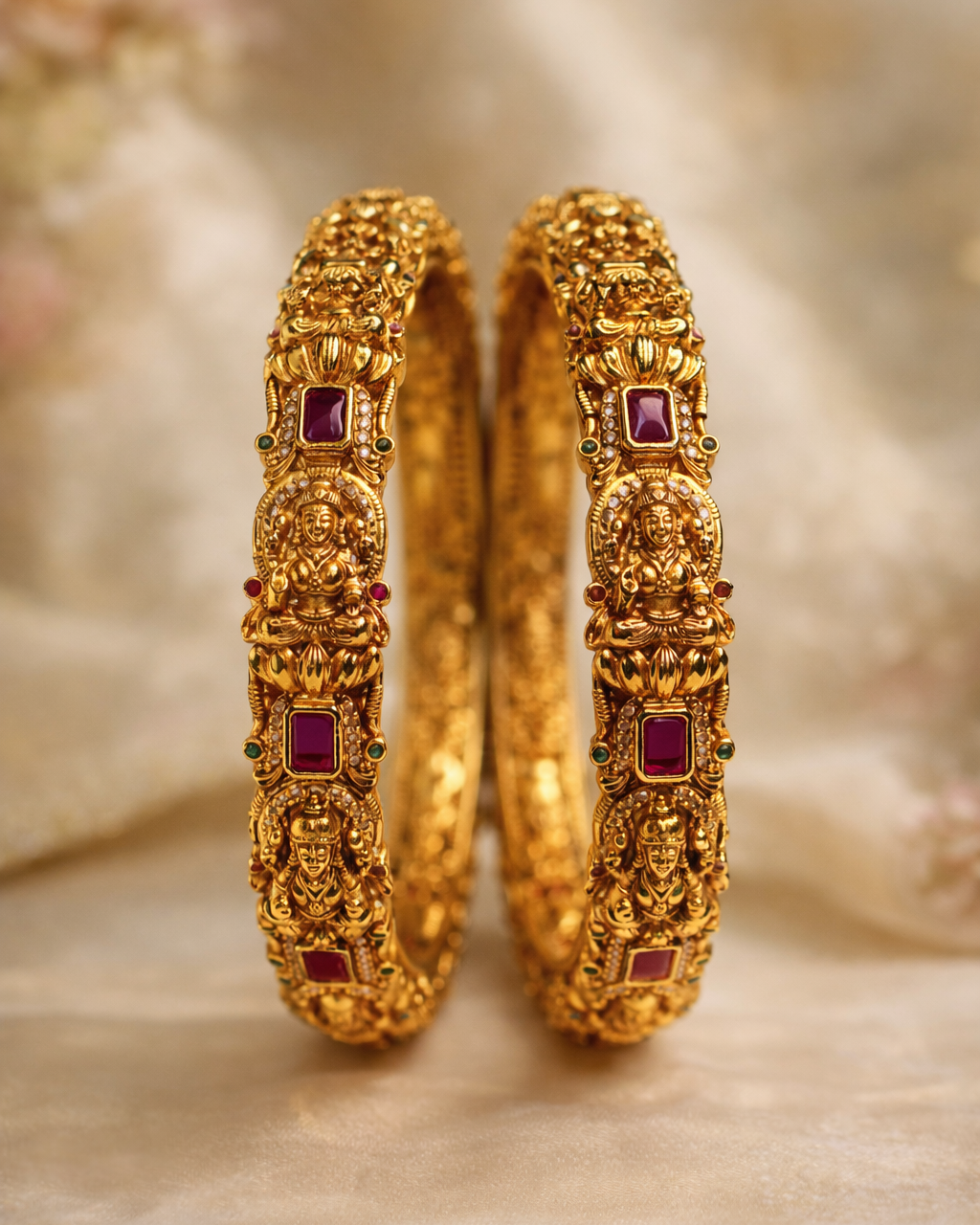 Pair of gold bangles with red gemstones on a soft, blurred  suwarnikaa jewels background