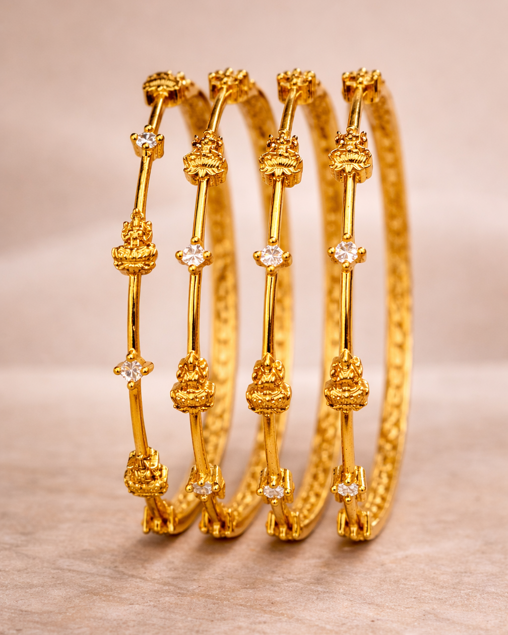 Set of gold bangles with decorative elements on a light wooden surface